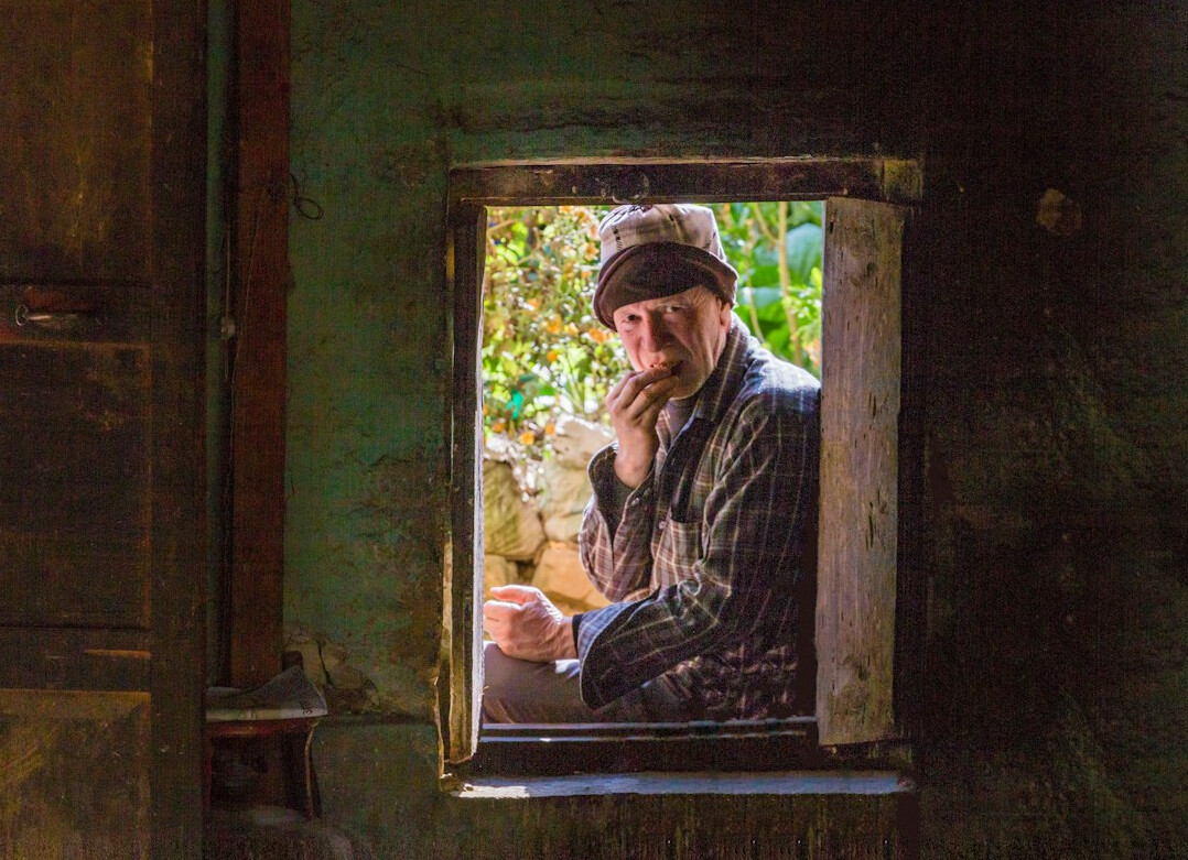 Elderly man being interviewed and photographed in his rural home