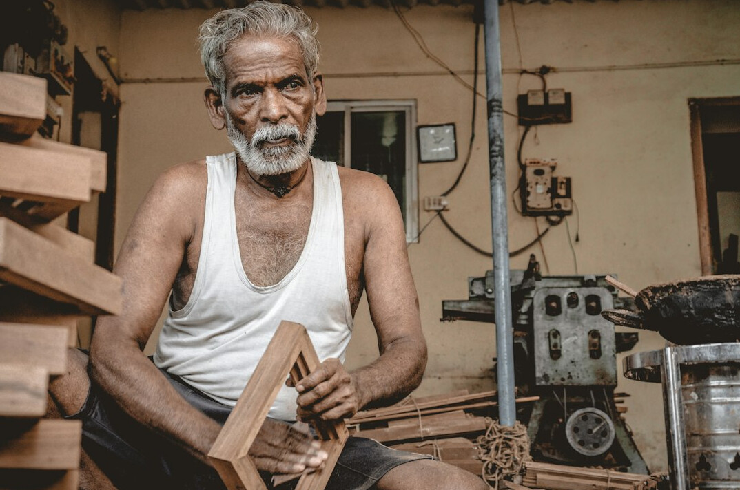 Elderly craftsman working with wood tools in a small workshop